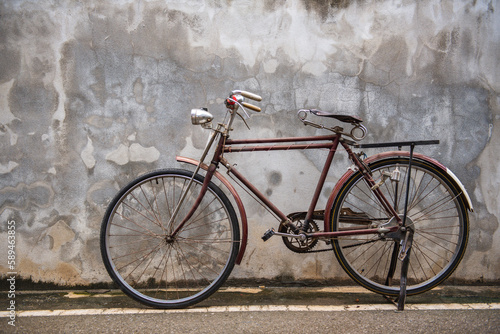 Vintage bicycle on old rustic dirty wall house, many stain on wood wall. Classic bike old bicycle on decay brick wall retro style. Cement loft partition and window background.