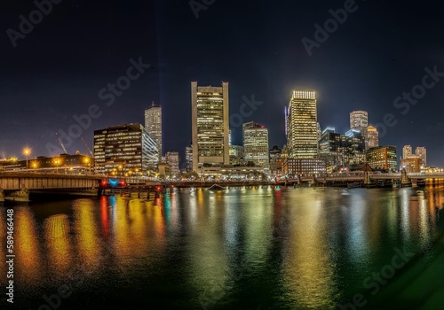 the lights on the buildings are shining brightly over the water © Owl Post Photography/Wirestock Creators