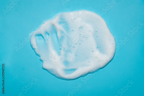 White lather foam moisturizer cream lotion cleanser on blue background. Beauty sudge smear mockup