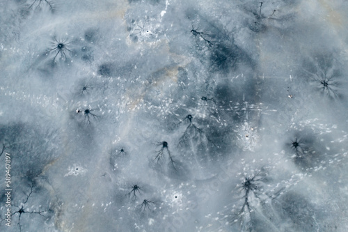 Top view of the frozen ice surface of the winter lake. Frozen pattern texture stripes and holes 