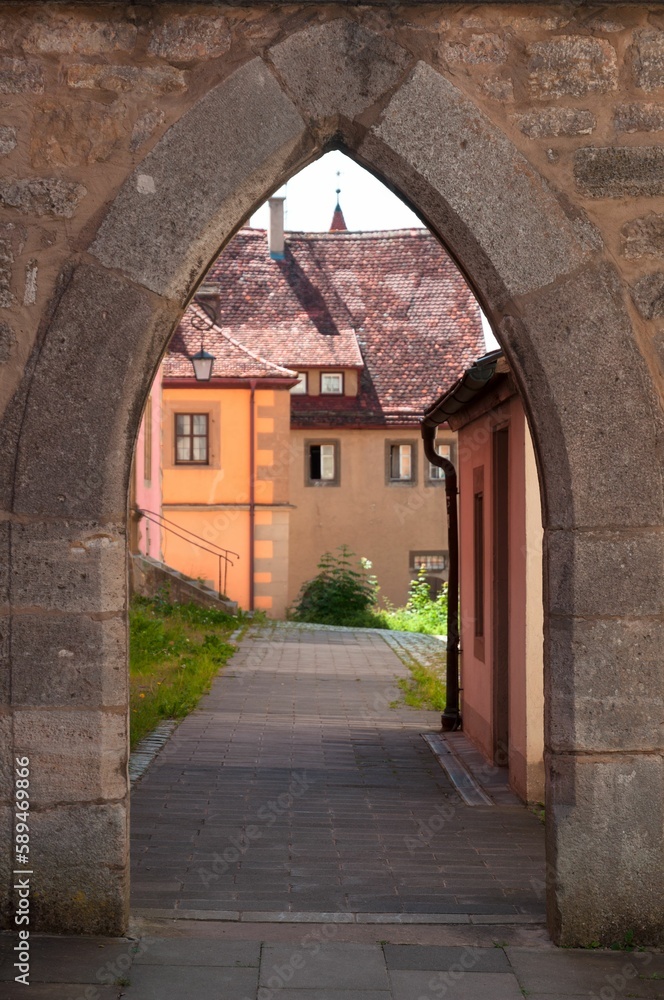 View through an archway to a house with old architecture