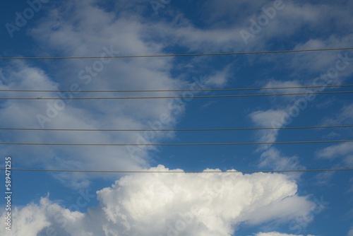 Low angle shot of electrical wires in a cloudy blue sky