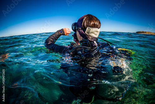 Scuba Diver Checks Dive Computer on Ocean Surface © feel4nature