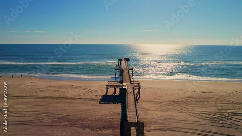 Drone shot of a wooden pier on a sandy beach with beautiful view of the seascape on a sunny day photo