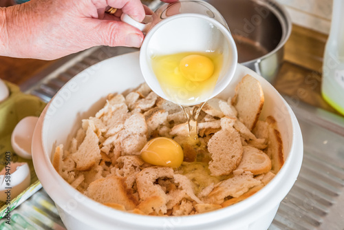 Gutbürgerliche Hausfrau Frau Köchin in der Küche schüttet Eier getrennt Eigelb von Eiweiß mit einer Tasse um mit Semmelbrösel Semmelknödel herzustellen, Deutschland photo