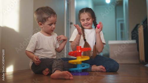 children baby play together toys in kindergarten. happy family preschool education indoor concept. baby boy and girl play toy roll a ball down a slide on lifestyle the floor rejoice in kindergarten