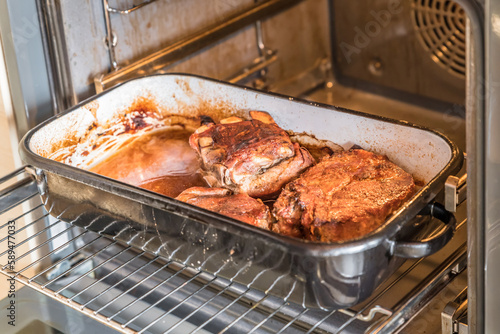 Real hearty homemade roast pork is cut into portions on a wooden board in the kitchen, Germany