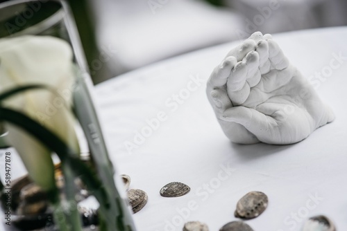 Closeup of an statuette of hands on one another on the white table, blurred background