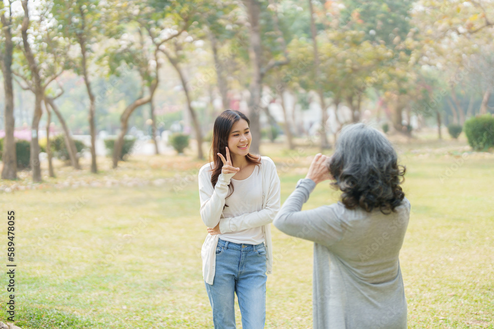 Asian teenage mother and daughter walking in park with camera to capture memories Asian teenage mother and daughter walking in park with camera to capture memories