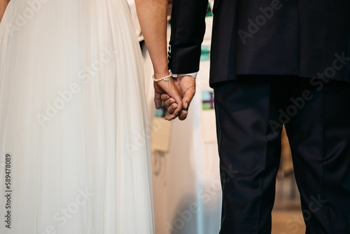 Closeup of the bridegroom holding bride s hand while standing next to her