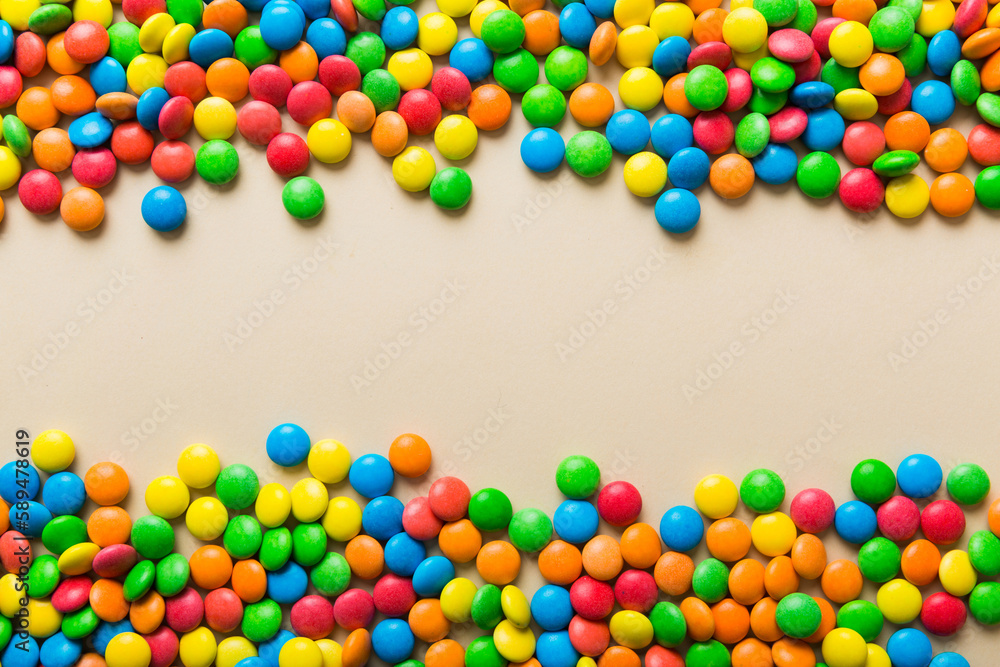 Obraz premium Mixed collection of colorful candy, on colored background. Flat lay, top view. frame of colorful chocolate coated candy