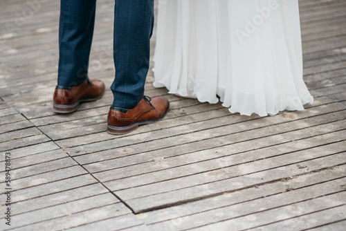 Closeup shot of grooms and brides legs on a wooden planks floor during their dance