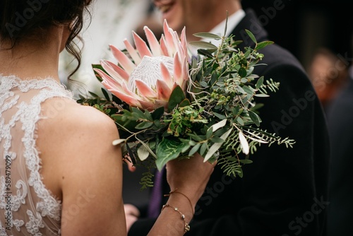 Shallow focus shot of a bride holding a bouquet with a king protea flower