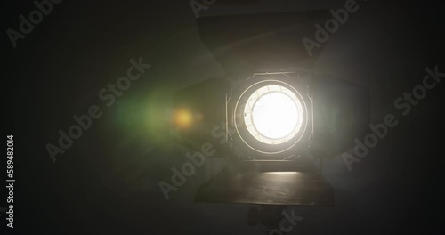 close up view of professional light source yellow color for filming, sunlight in dark room with smoke around. professional fresnel lens is mounted on video light. photo