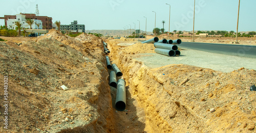 фотографія EGYPT, MARSA ALAM-FEBRUARY 24, 2019: laying plastic water pipes in the sand alon