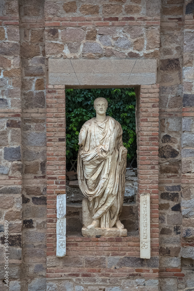 Statue of Roman man in ruins niche municipal forum of Augusta Emérita, Roman ruins of 1st-century structure with Corinthian columns and historic statues