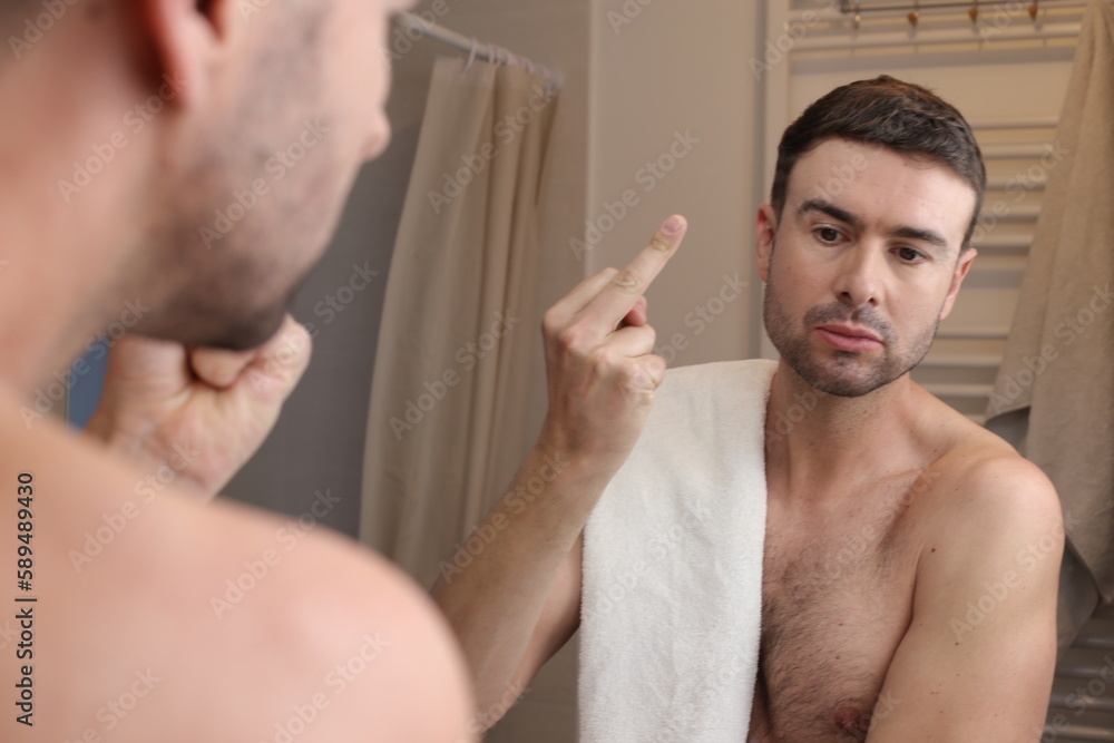 Fototapeta premium Man showing middle finger in the bathroom mirror