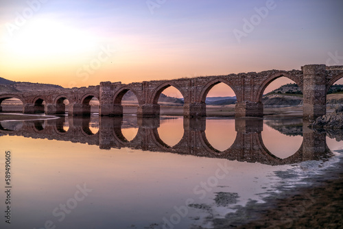 La Mesta bridge of medieval construction over the Guadiana river at sunrise in the Cjara reservoir in the province of Badajoz, Spain