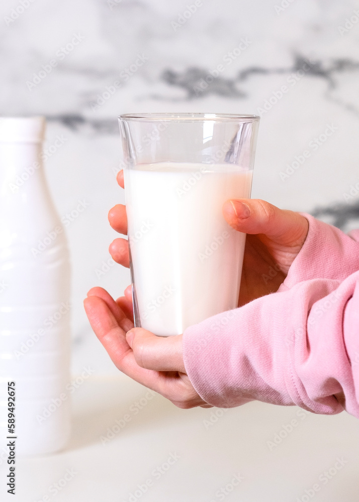 female hands hold a glass of milk in the background a white bottle female hands hold a glass of milk in the background a white bottle