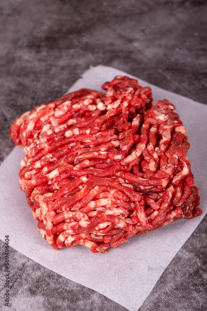 Minced meat on butcher paper. Fresh ground beef on wood background. Close up Minced meat on butcher paper. Fresh ground beef on wood background. Close up