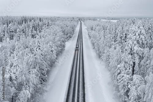 Overhead view of car driving on slippery empty road in the snowy forest, Lapland, Finland