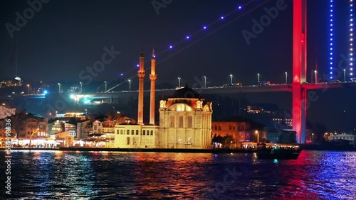 View of Bosporus strait at night in Istanbul, Turkey. Nusretiye Mosque, illuminated bridge with cars, buildings on the background photo
