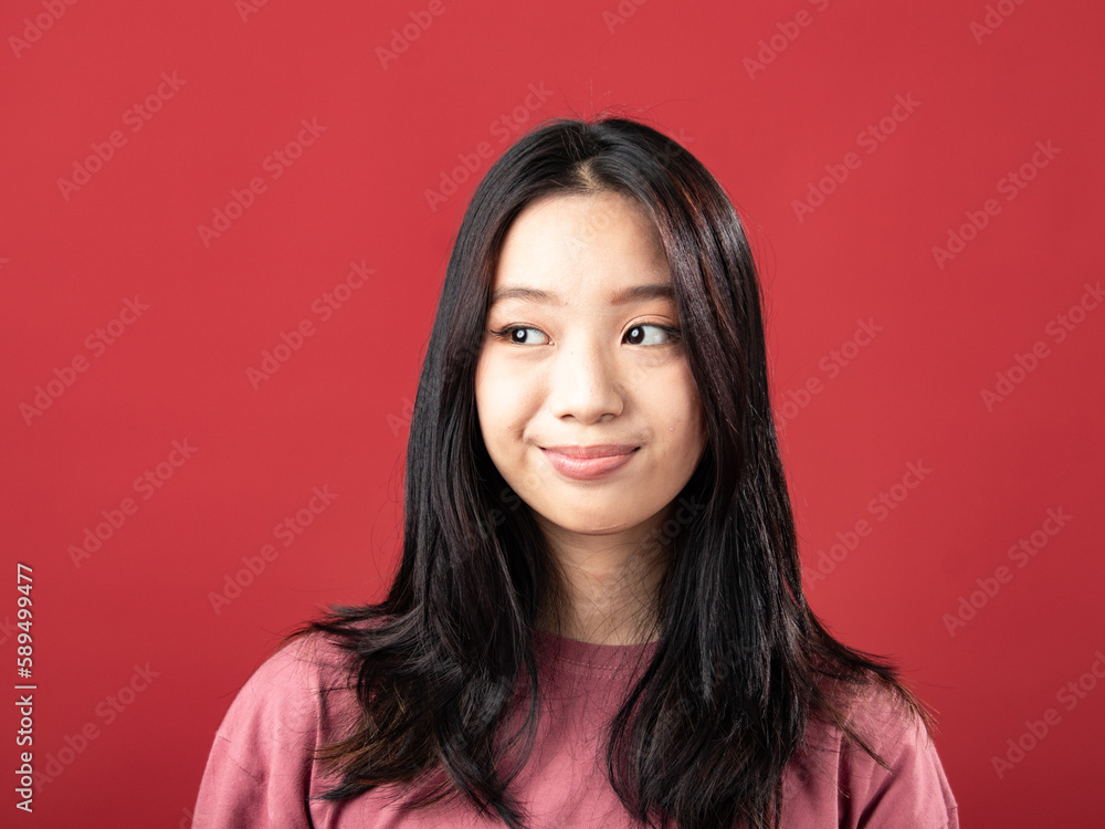 A close-up portrait of a young Indonesian (Asian) woman wearing a pink shirt. Isolated with a red background A close-up portrait of a young Indonesian (Asian) woman wearing a pink shirt. Isolated with a red background