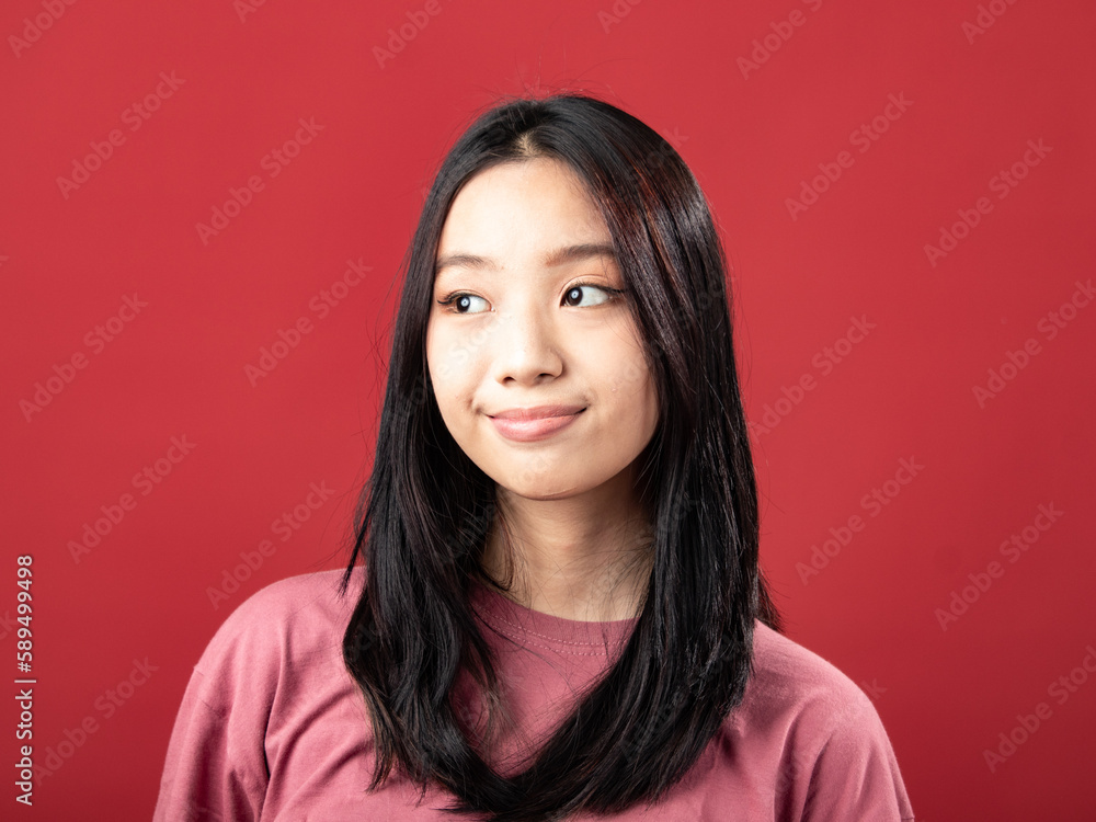 A close-up portrait of a young Indonesian (Asian) woman wearing a pink shirt. Isolated with a red background A close-up portrait of a young Indonesian (Asian) woman wearing a pink shirt. Isolated with a red background