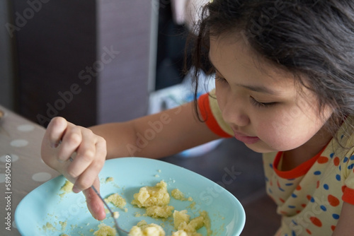Girl having breakfast and eating oatmeal porridge