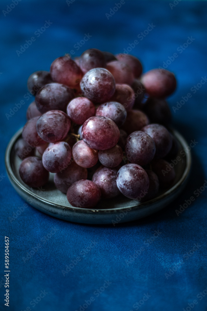 Dark grapes on a plate and on abstract blue watercolor background Dark grapes on a plate and on abstract blue watercolor background