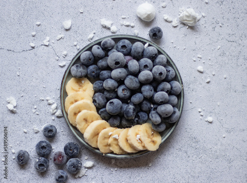 Frozen blueberries and banana on a plate and abstract background