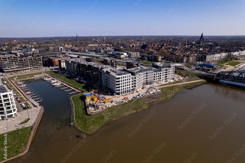 Aerial view of luxury Kade Zuid apartment complex construction at riverbank of river IJssel between train tracks and recreational port. 