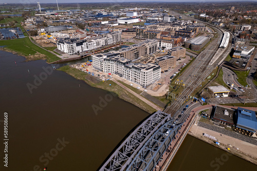 River IJssel passing by Dutch Hanseatic city of Zutphen, The Netherlands, with a steel train and traffic draw bridge and new-build neighbourhood Noorderhaven in the background