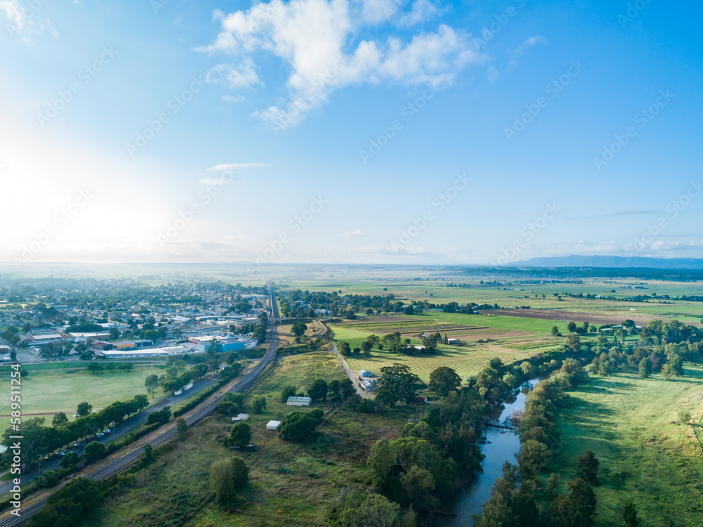 Aerial view of morning light over railway line and river with farm paddocks at edge of town Aerial view of morning light over railway line and river with farm paddocks at edge of town