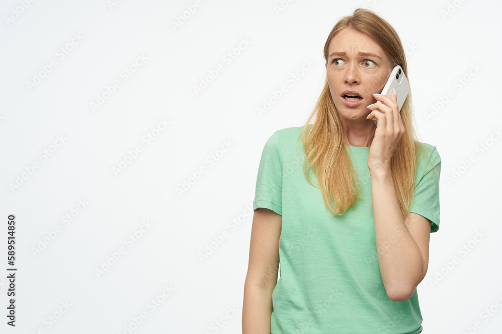 Indoor studio portrait of young ginger female with freckles talking with boyfriend with sad facial expression, isolated over background Indoor studio portrait of young ginger female with freckles talking with boyfriend with sad facial expression, isolated over background