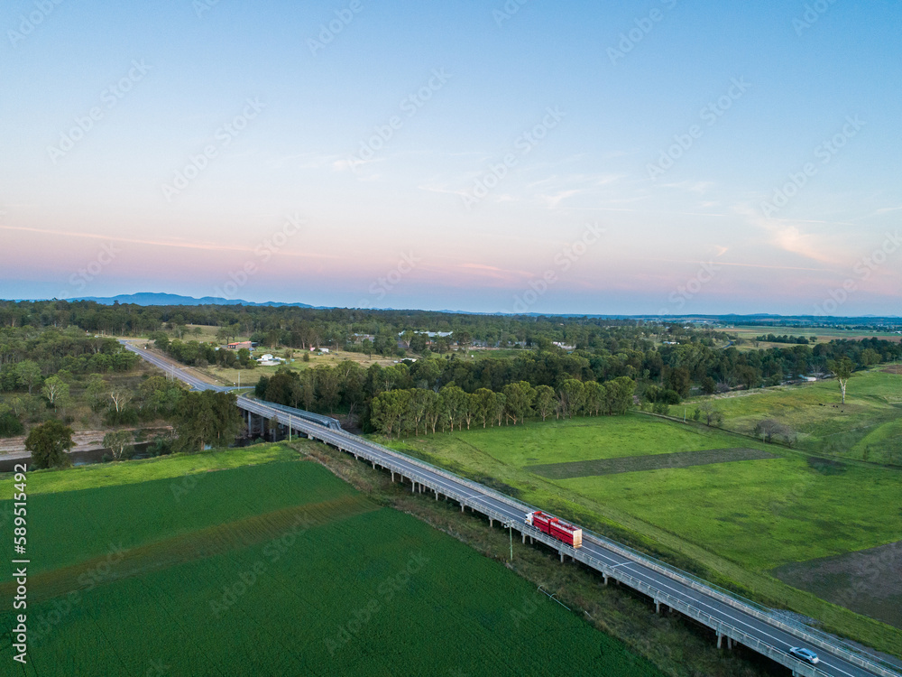 Red cattle truck on bridge travelling through green farmland in country Red cattle truck on bridge travelling through green farmland in country
