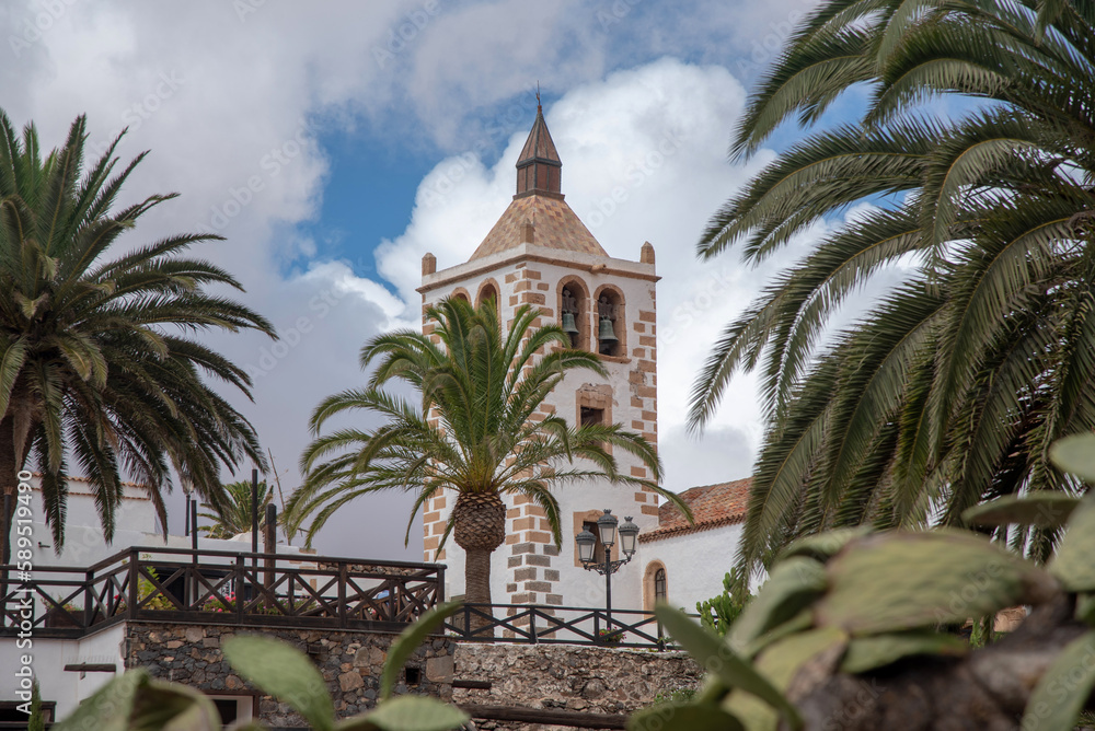 Detalle del campanario de la iglesia blanca del pueblo de Betancuria, rodeado de muchas palmeras y algunos cactus en Fuerteventura Islas Canarias