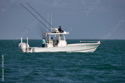 Three fishermen on a center console fishing boat in the ocean.