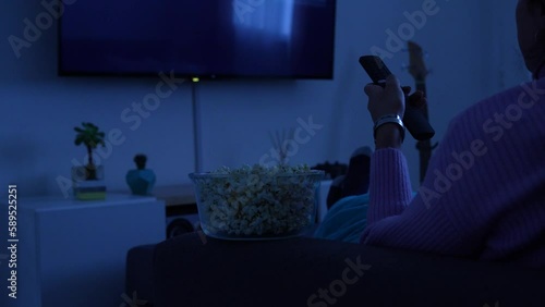 Woman watching Netflix on the sofa of her living room while eating popcorn. July 12, 2022. Rio Negro, Argentina photo