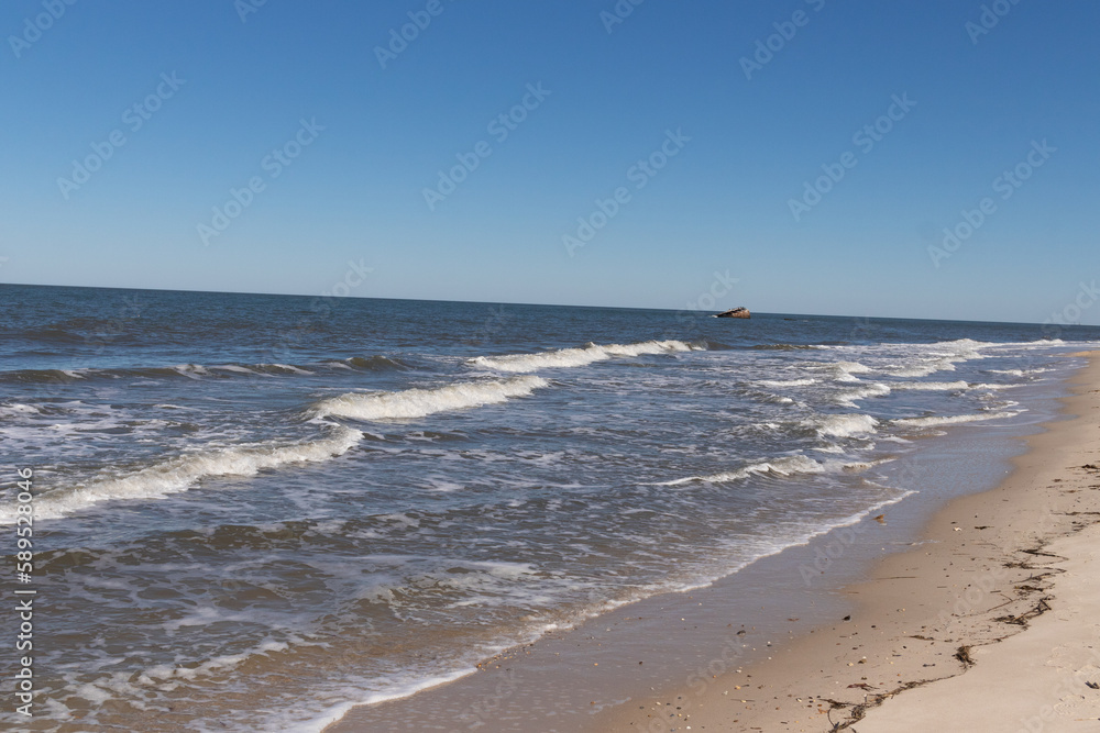 I love this look of the waves battering the beach. The white caps of the surf as it pummels the sand. The beautiful cloudless sky in the background makes the pretty sea stand out. This is Cape May.