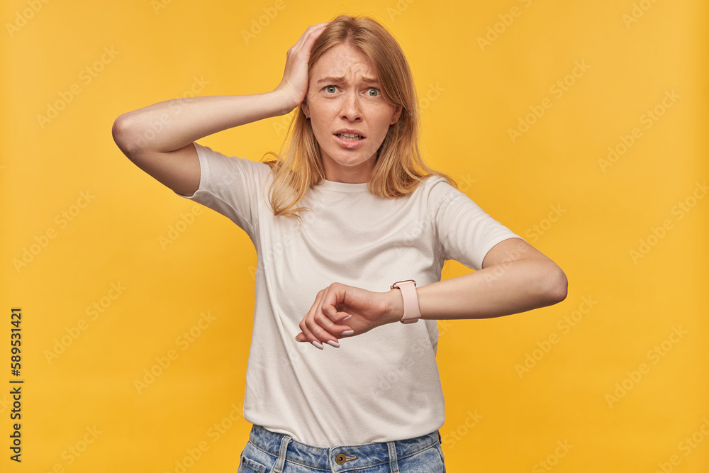 Indoor studio portrait of young ginger female with freckles late for work, isolated over yellow orange background Indoor studio portrait of young ginger female with freckles late for work, isolated over yellow orange background