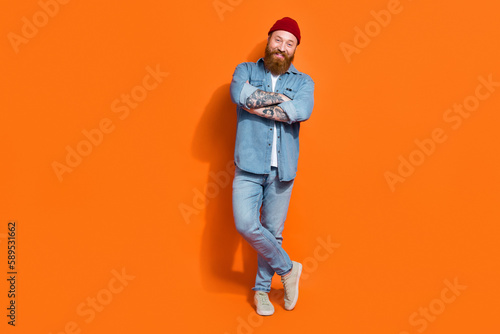 Full length photo of funky confident man wear jeans shirt arms crossed empty space isolated orange color background