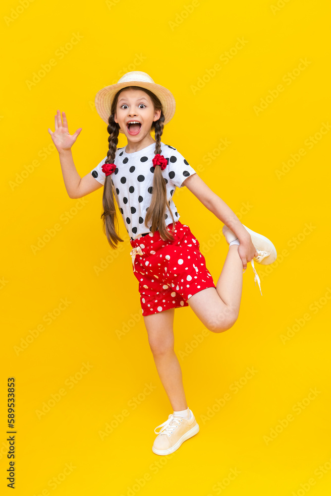 A wonderful little girl is playing in a straw hat and shorts. A beautiful child is enjoying the summer and smiling broadly and fooling around on a yellow isolated background. A wonderful little girl is playing in a straw hat and shorts. A beautiful child is enjoying the summer and smiling broadly and fooling around on a yellow isolated background.