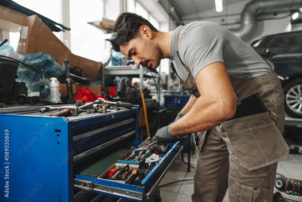 Male technician standing near tool table in car service Male technician standing near tool table in car service