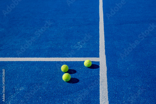 three balls on a blue paddle tennis court, racket sports background © Vic