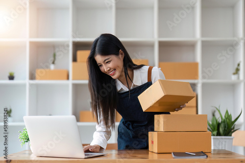 Startup SME small business entrepreneur of freelance Asian woman using laptop and box to receive and review orders online to prepare to pack sell to customers, online sme business ideas