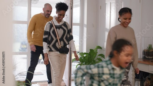 Family arriving home with French bulldog running through hall