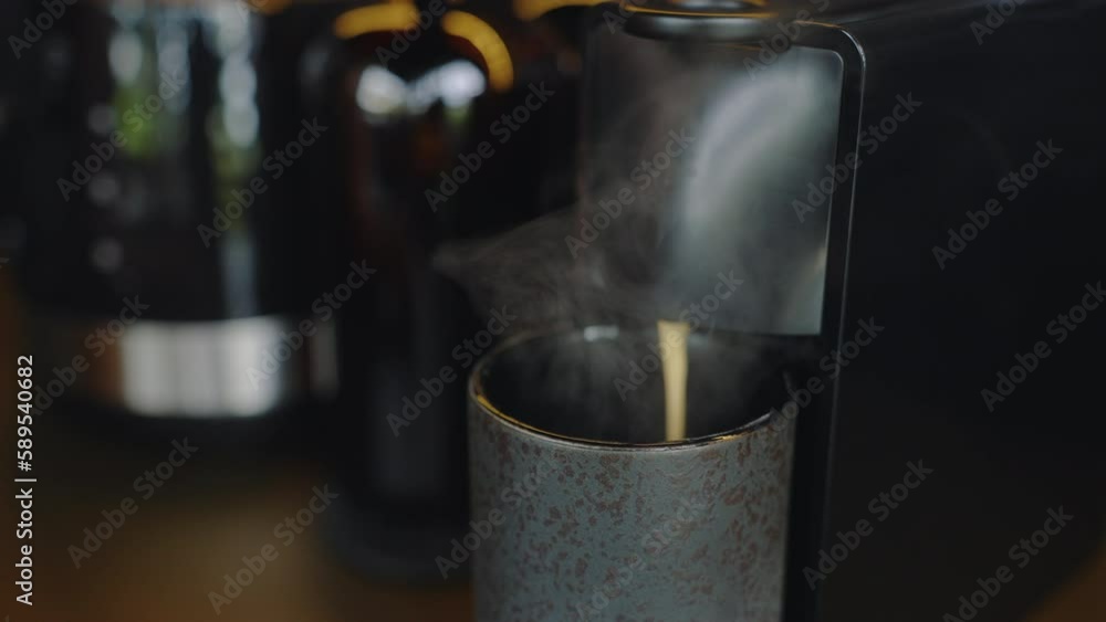 Making coffee with capsule coffee machine. Breakfast details in the morning in domestic private kitchen. Cappuccino pouring into cup Making coffee with capsule coffee machine. Breakfast details in the morning in domestic private kitchen. Cappuccino pouring into cup