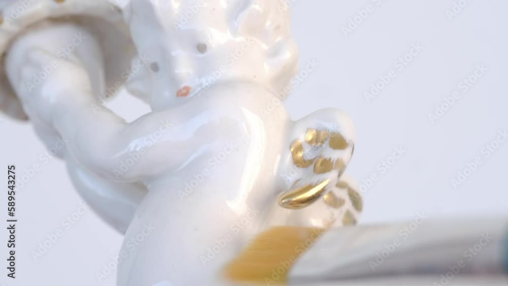 professional restorer at work on white porcelain figurine, candlestick Small cupid of Love with golden wings, cleans glaze with soft brush angel miniature, concept of restoring ancient sculptures professional restorer at work on white porcelain figurine, candlestick Small cupid of Love with golden wings, cleans glaze with soft brush angel miniature, concept of restoring ancient sculptures