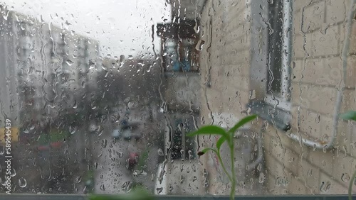 It's raining outside the window of the house, drops on the glass